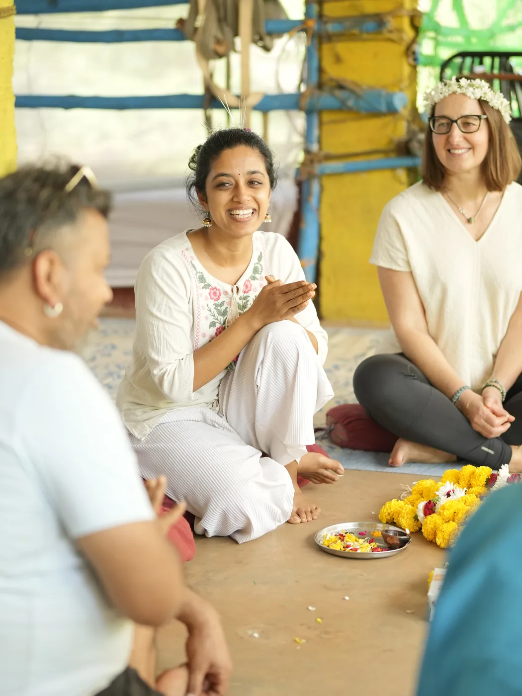 Students and teachers laughing together in a seated circle during a ceremony at Alpesh Yoga