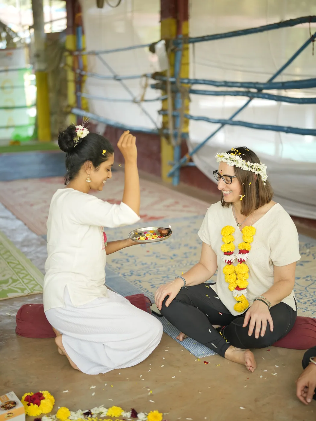 Student receiving a tilak blessing from a teacher holding a puja plate during an Alpesh Yoga ceremony at the Arambol shala