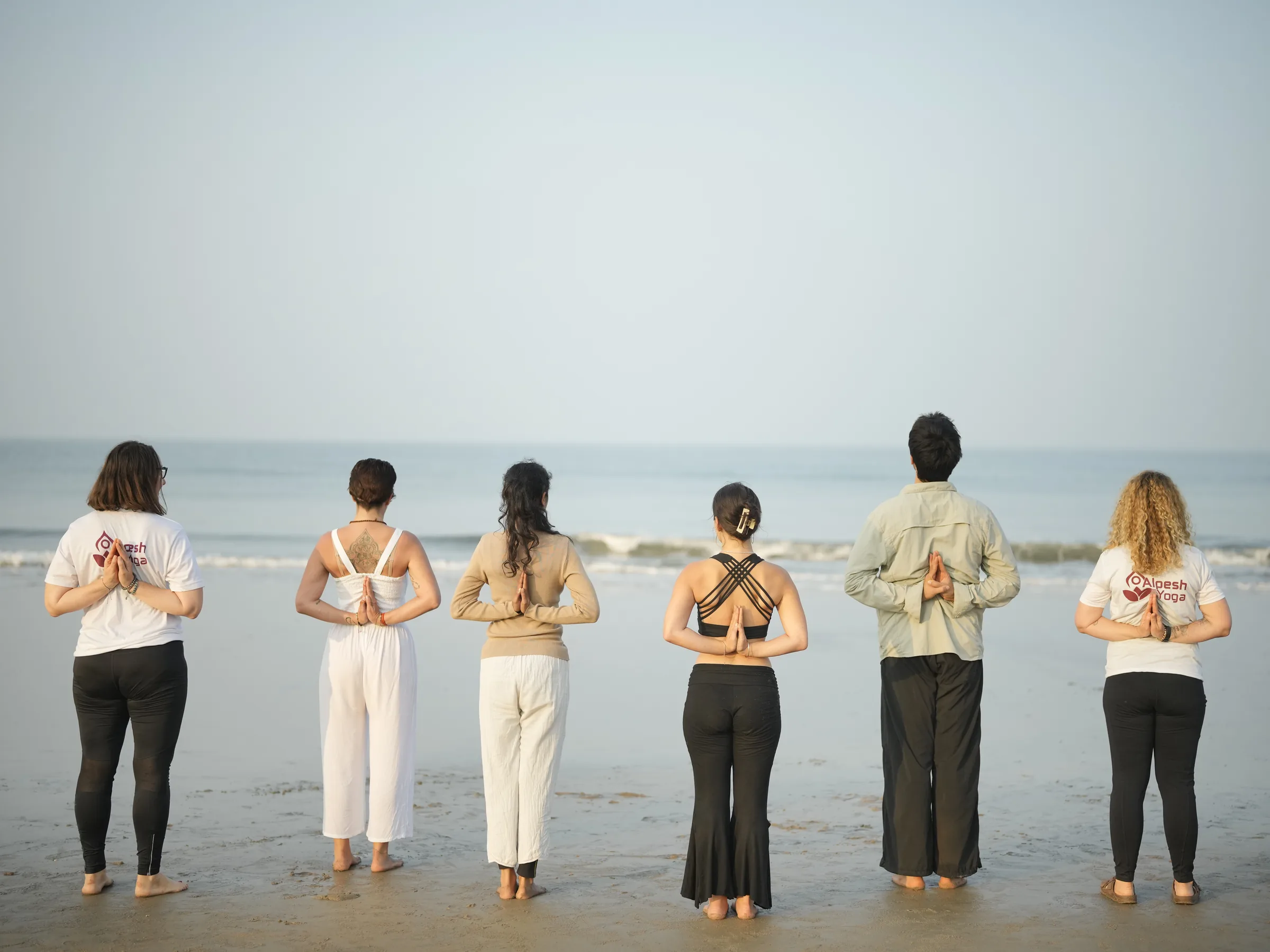 Yoga teacher training class practising together on Arambol Beach, Goa
