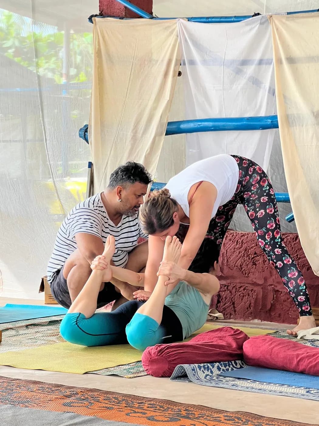 Two teachers giving a hands-on assist in a seated forward fold during teaching practice