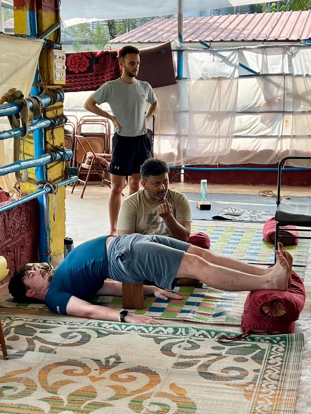 Student in a supported bridge with a wooden block under the sacrum and a bolster beneath the legs