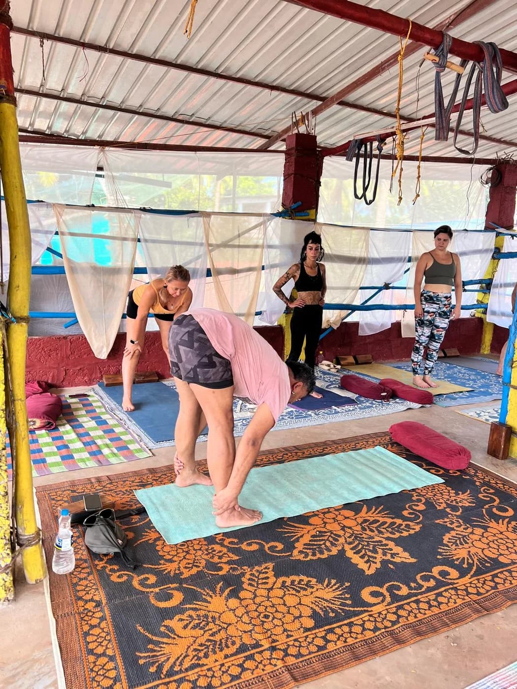 Yoga students folding forward on their mats during a group practice at the Arambol shala