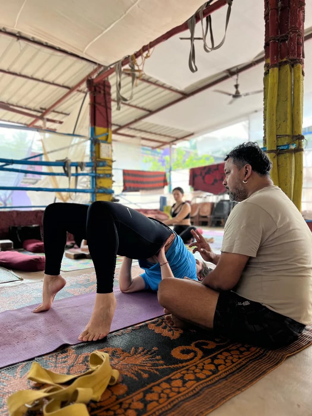Teacher talking a student through Setu Bandha, the bridge pose, at the Arambol shala